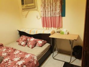 Kleines Zimmer mit einem Bett und einem Tisch in der Unterkunft Bzxmax Guest House in al-Ain
