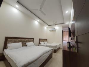 a bedroom with two beds and a tv in it at New Gokul Grand in Dehradun