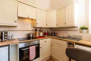 una cucina con armadi bianchi e lavandino di Luxury Apartment - 18 Lansdown Crescent a Cheltenham