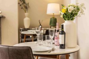 a table with wine glasses and a vase with flowers at Luxury Apartment - 18 Lansdown Crescent in Cheltenham