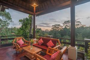 a porch with chairs and a table with a view at Villa Awang - awang in Ubud