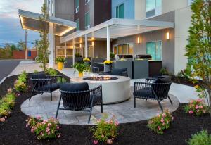 un patio avec des chaises et un foyer extérieur en face d'un bâtiment dans l'établissement TownePlace Suites Portland Airport ME, à South Portland