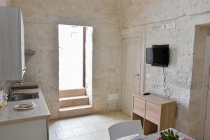 a kitchen with a sink and a tv on the wall at Agape fra i Trulli Dimora Orchidea in Alberobello