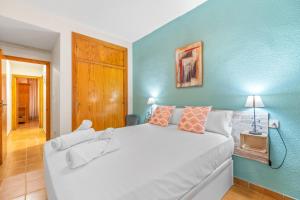 1 dormitorio con 1 cama blanca grande y pared azul en Sunflower Gaviotas, en Santa Pola