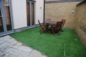 a patio with a table and chairs on grass at Modern flat Tower Bridge/Bermondsey in London