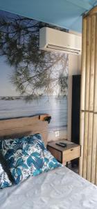 a bedroom with a bed and a wall with a tree at Studio de charme à 300 m de la Plage de Santa Giulia in Porto-Vecchio