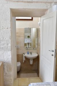 a white bathroom with a sink and a toilet at Agape fra i Trulli Dimora Orchidea in Alberobello