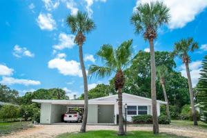 a house with palm trees in front of it at Cozy cottage for longer stays! in Vero Beach