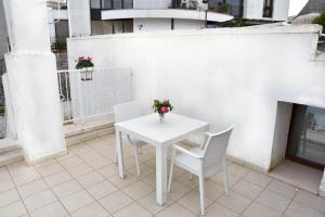a white table with two chairs and a vase with flowers at Agape fra i Trulli Dimora Orchidea in Alberobello