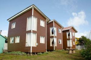 Casa de madera grande con ventanas blancas en un patio en CABAÑAS LAS DALIAS ANCUD, en Ancud