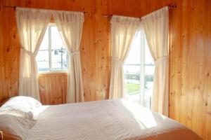 1 dormitorio con cama y ventana grande en CABAÑAS LAS DALIAS ANCUD, en Ancud