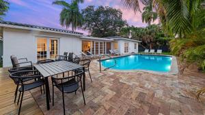 a patio with a table and chairs and a swimming pool at Villa Seabreeze in Fort Lauderdale