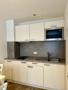 a white kitchen with a sink and a microwave at SKILL Mountain Lodge - Ski und Bike Hostel inklusive JOKER CARD in Saalbach-Hinterglemm