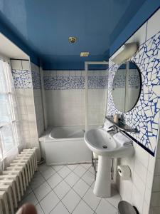 uma casa de banho com um lavatório e uma banheira em LOGIS Hôtel & Restaurant - Les Bords de Seine em La Roche-Guyon