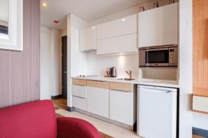 une cuisine avec des placards blancs et un canapé rouge dans l'établissement Lux Residence w Balcony 1 min to Metro in Merter, à Istanbul