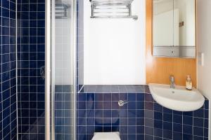 a blue tiled bathroom with a sink and a toilet at Modern and spacious 2-BR, 2-BA retreat near Tower Bridge in London