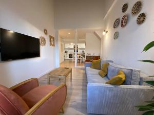 a living room with a couch and a tv on a wall at T3 bord canal du midi, piscine in Homps
