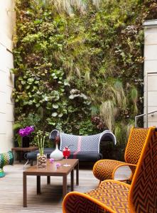 un patio con sillas y mesas y una pared con plantas. en Hotel C2, en Marsella