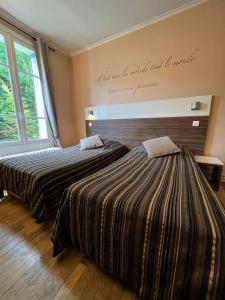 duas camas num quarto com uma placa na parede em LOGIS Hôtel & Restaurant - Les Bords de Seine em La Roche-Guyon
