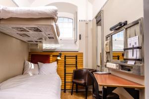 Cette petite chambre comprend un lit, un bureau et des lits superposés. dans l'établissement STF Långholmen Hostel, à Stockholm