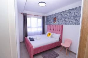 a small bedroom with a pink bed and a pink chair at The Gold Park 2 bedroom Kilimani in Nairobi