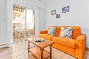 a living room with an orange couch and a table at Sunflower Club Náutico in Santa Pola