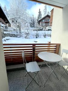 a table and two chairs on a balcony with a snow covered yard at Cozy apartment in St. Moritz in St. Moritz