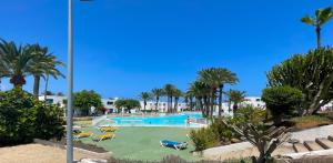a pool with slides and palm trees in a resort at Los Barqueros 25 by Best Holidays Fuerteventura in Corralejo