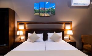 a bedroom with a bed with white sheets and pillows at Woodgrove Cabanas in Negombo