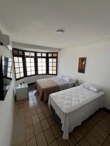 a bedroom with two beds and two windows at Pousada Mangai in João Pessoa