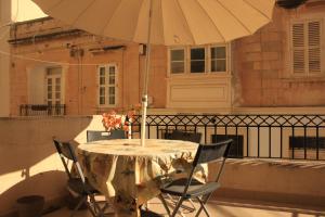 a table and chairs with an umbrella on a balcony at Door 51 in St. Julianʼs