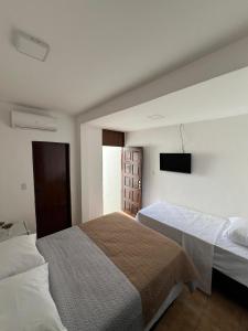 a bedroom with two beds and a flat screen tv at Pousada Mangai in João Pessoa
