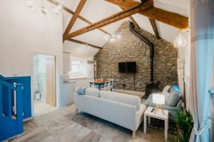 a living room with a white couch and a stone wall at The Cow Shed at Pencraig in Holyhead