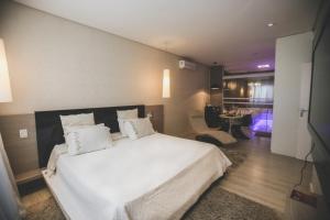 ein Schlafzimmer mit einem weißen Bett und ein Wohnzimmer in der Unterkunft Gontijo Inn Hotel in Itajubá