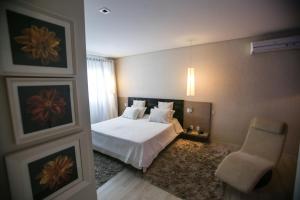 イタジュバにあるGontijo Inn Hotelの白いベッドと椅子のある寝室