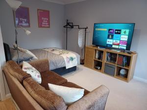 a living room with a couch and a flat screen tv at The Highland Studio Muir of Ord in Muir of Ord +17 photos