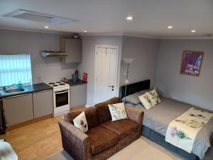 a living room with a couch and a kitchen at The Highland Studio Muir of Ord in Muir of Ord