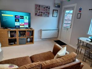 a living room with a couch and a flat screen tv at The Highland Studio Muir of Ord in Muir of Ord