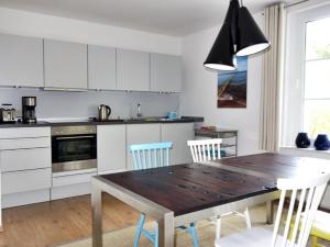 a kitchen with a wooden table and white cabinets at Ringstrasse 1 in Kölpinsee