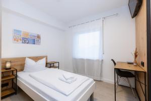um quarto com uma cama branca e uma secretária em Hotel Villa Positano em Riedstadt