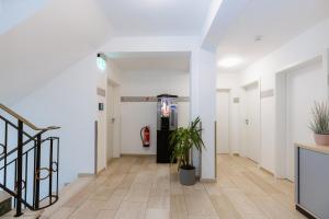 un couloir vide avec des murs blancs et une plante en pot dans l'établissement Hotel Villa Positano, à Riedstadt