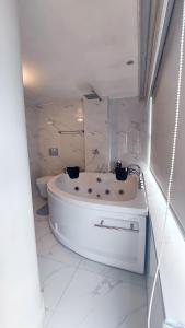 a white bathroom with a tub and a toilet at HOTEL REAL PLAZA in Cajamarca