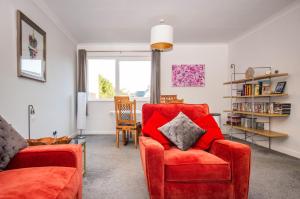 a living room with a red couch and a chair at 2 bed spacious, light & quiet flat, free parking in Heaton