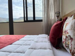 a bed with red pillows and a window in a room at Hotel Cinco Diamantes in Atotonilco el Alto