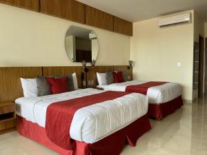 two beds in a hotel room with a mirror at Hotel Cinco Diamantes in Atotonilco el Alto