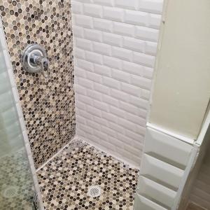 uma casa de banho com um chuveiro com azulejos pretos e brancos em STUDIO and ONE BEDROOM APARTMENTS em Bronx