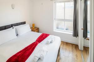 a bedroom with a white bed with a red blanket on it at The Bright Flat in Whitechapel in London
