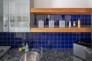 a kitchen with a sink and a blue tiled wall at The Bright Flat in Whitechapel in London