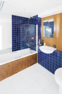 a blue tiled bathroom with a tub and a sink at The Bright Flat in Whitechapel in London