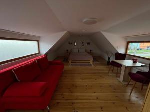 a living room with a red couch and a bed at Pensiunea CASA HANN in Apold